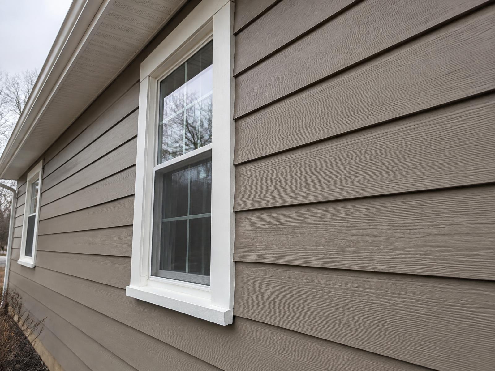 Close-up example of new lap siding meeting a white window casing and white soffit