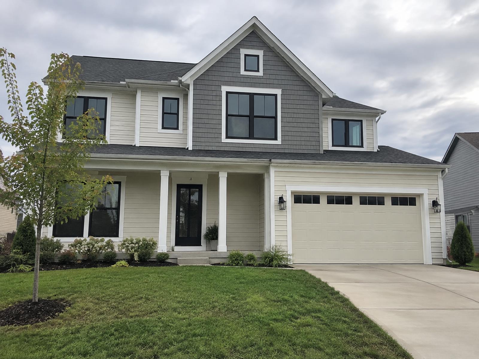 Example of a Kansas City home with cream lap siding and gray shake accents in the front gable